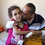 Suzy Ishkontana, 7 tahun, dicium ayahnya, Riad Ishkontana, 42, di Rumah Sakit Shifa di Kota Gaza, Selasa, 18 Mei 2021. (Foto: AP/Abdel Kareem Hana)