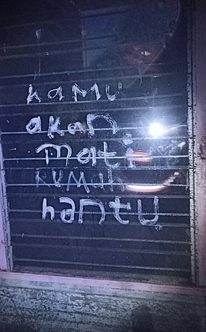 Kaca rumah yang terbakar bertuliskan, Kamu Akan Mati Rumah Hantu. (foto: rohan)
