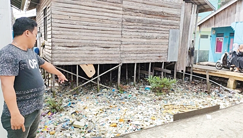 Warga menunjukkan kondisi sampai yang mengelilingi permukiman penduduk di Desa Rampa, Kabupaten Kotabaru. (foto: icah)