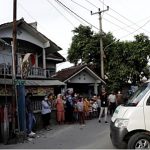 Seorang sukarelawan mengenakan APD terlihat di dalam ambulans, mengangkut korban COVID-19 yang meninggal dunia saat isoman di rumahnya, disaksikan penduduk setempat dari kejauhan di lingkungan Mulyaharja, Bogor, Jawa Barat, 8 Juli 2021. (REUTERS/Willy Kurniawan)