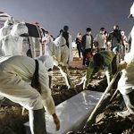 Penggali kubur mengenakan alat pelindung diri (APD) mengubur peti mati saat kerabat berdiri di belakang pemakaman Muslim yang disediakan pemerintah untuk korban COVID-19, di Jakarta, 7 Juli 2021. (Foto: REUTERS/Willy Kurniawan)