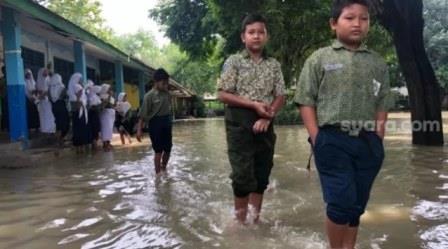Sejumlah siswa SD Negeri 99 Gresik tetap bersekolah meski dilanda banjir, Rabu (1/12/2021). (SuaraJatim.id/Amin Alamsyah)