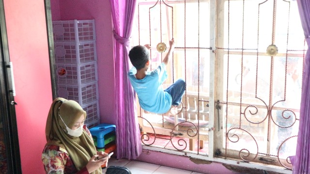 Seorang anak mencontohkan hukuman bergantung di teralis kepada petugas Dinas Perlindungan Anak. (Sumber Foto: Ari/Koranbanjar)