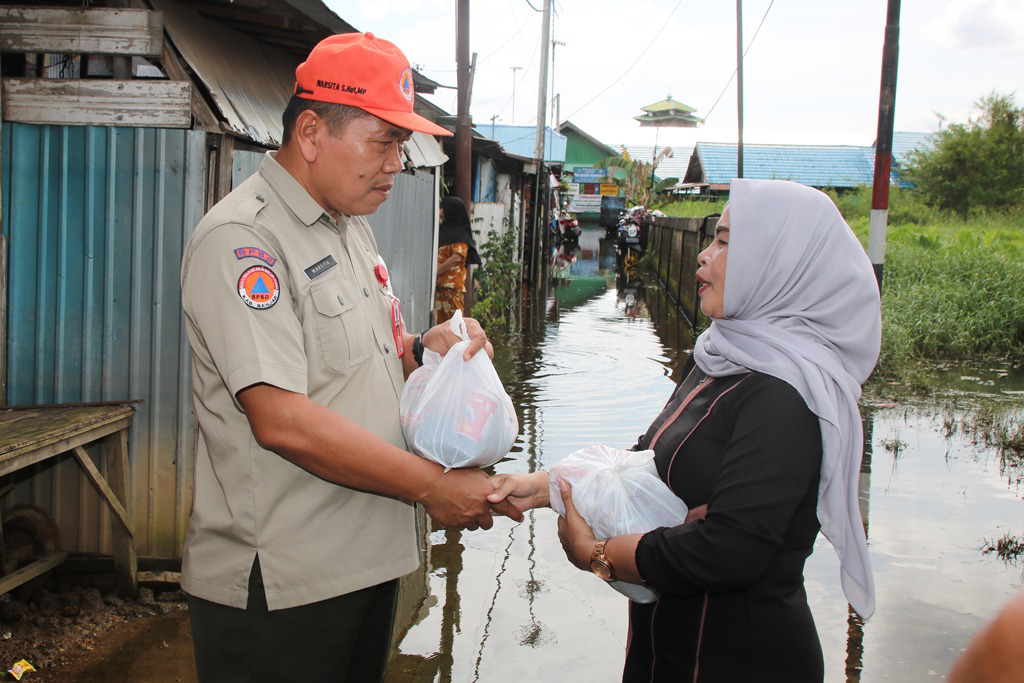 Kepala Pelaksana BPBD Kabupaten Banjar, Warsita (kiri) memberikan bantuan sembako kepada warga terdampak banjir. (Foto: Kominfo Kabupaten Banjar/Koranbanjar.net)