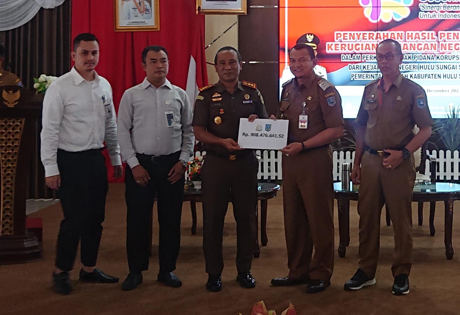Penyerahan secara simbolis dari Kajari HSS Nul Albar kepada Pj Bupati HSS Hermansyah, berupa uang pengembalian tindak pidana korupsi, Senin (11/12/2023). (Foto: Devi/Koranbanjar.net)